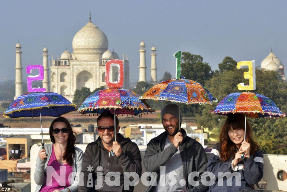 Tourists pose as they carry umbrellas with numbers to welcome the New Year 2013 on the terrace of a 